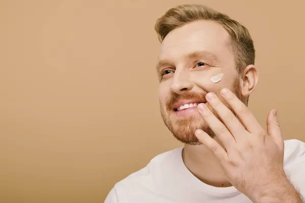 Handsome man in casual attire with a patch of cream on his face. — Stock Photo