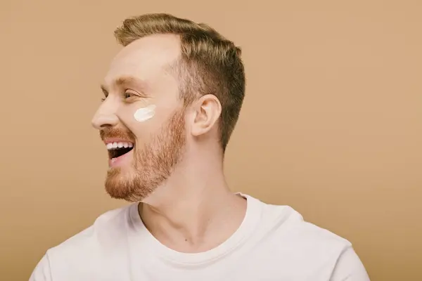 A bearded man wearing a white face cream as part of his skincare routine. — Stock Photo