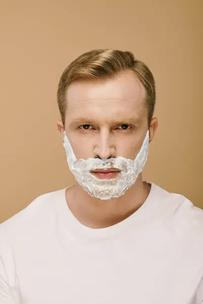 Un hombre barbudo con atuendo casual se afeita cuidadosamente la barba.. - foto de stock