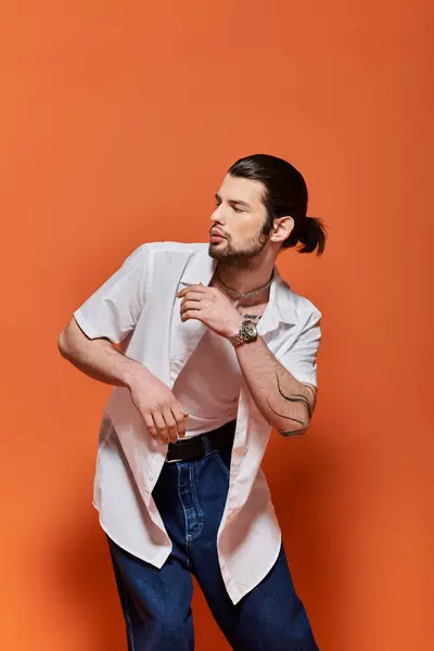 Un guapo caucásico vestido de moda delante de una pared naranja. — Stock Photo