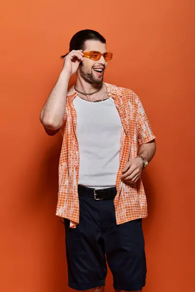 Handsome man in trendy attire, wearing white t-shirt and orange cardigan. — Stock Photo
