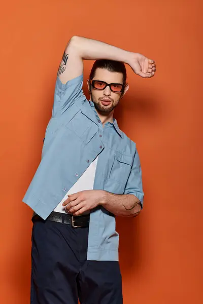 Uomo caucasico in camicia blu alla moda tiene tranquillamente le braccia dietro la testa. — Foto stock