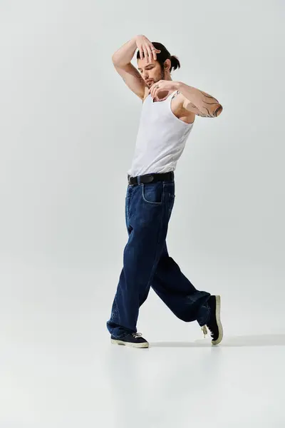 A stylish man in a white tank top is dancing confidently. — Stock Photo