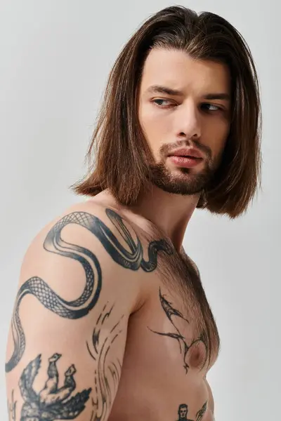 Handsome man with long hair showcasing a tattoo on his arm. — Stock Photo
