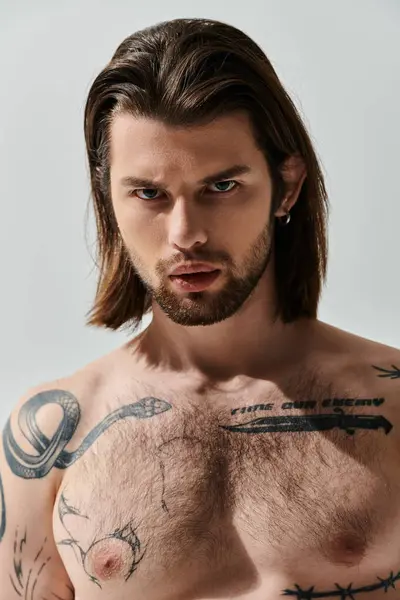 Un uomo caucasico con lunghi capelli e tatuaggi sul petto che mostra il suo lato ribelle. — Foto stock