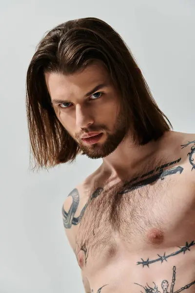 Caucasian man with long hair showcases chest tattoos. — Stock Photo