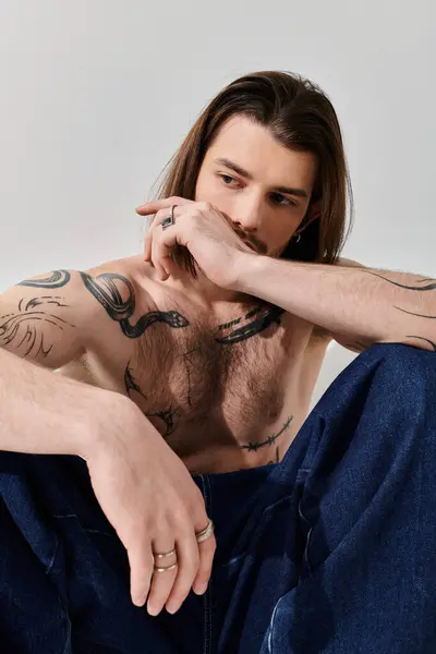 Trendy Caucasian man with long hair and chest tattoos. — Stock Photo