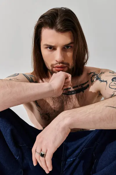 Bell'uomo caucasico con i capelli lunghi seduto con grazia a terra. — Foto stock