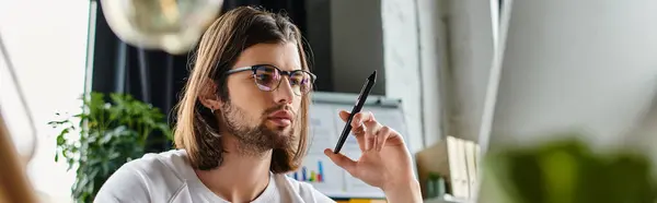 Handsome man with long hair and glasses using pen. — Stock Photo