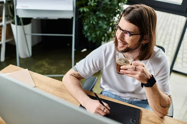 Man working on laptop and having a drink at desk. — Stock Photo