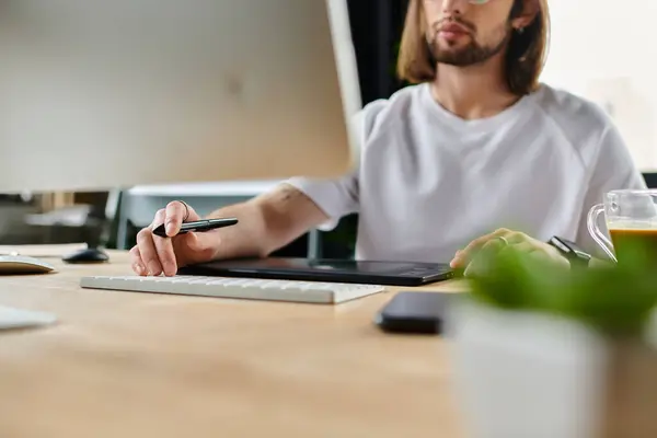 Un hombre de negocios caucásico absorto en el trabajo en su escritorio de la oficina con una computadora. - foto de stock