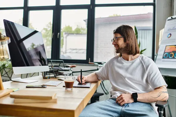 Un hombre de negocios se sienta en un escritorio, enfocado en su computadora en un entorno de oficina. - foto de stock