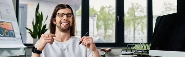 Handsome Caucasian businessman with long hair and glasses focused on work at computer. — Stock Photo