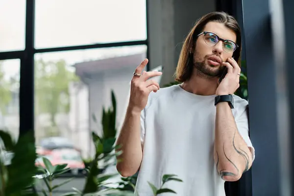 Caucásico hombre con el pelo largo y gafas hablando en un teléfono celular. - foto de stock