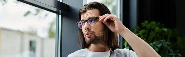 A man with long hair and sunglasses gazes out a window. — Stock Photo