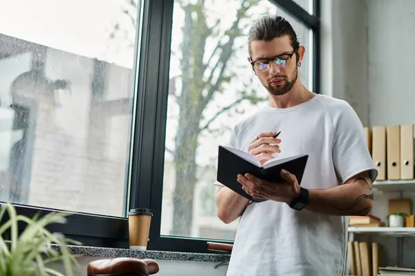 Man holding a book, stands by window. — Stock Photo