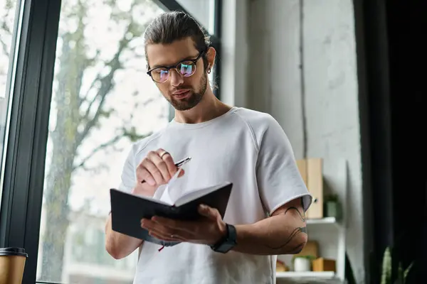 Caucasian businessman in white T-shirt writing on notebook. — Stock Photo