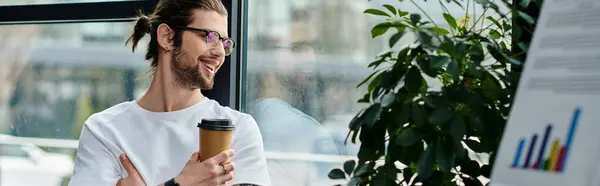 A handsome businessman sipping coffee by a window. — Stock Photo