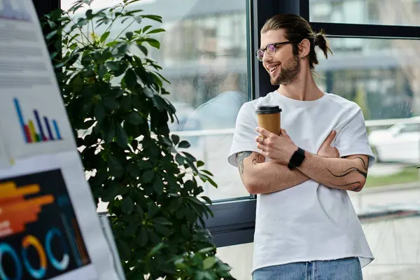 Un homme d'affaires, debout près de la fenêtre, tenant une tasse de café. — Photo de stock