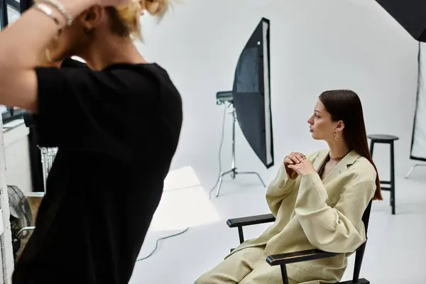 Una donna si siede vicino al suo truccatore in studio fotografico. — Foto stock