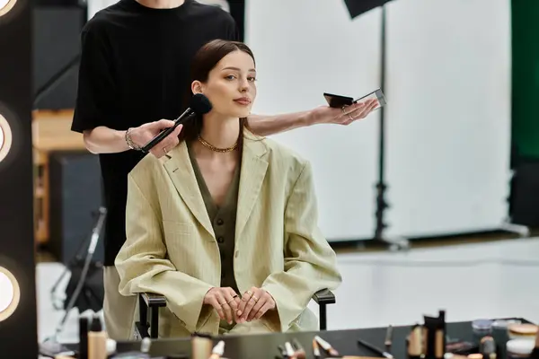 Una donna siede davanti a uno specchio come artista crea un look mozzafiato. — Foto stock