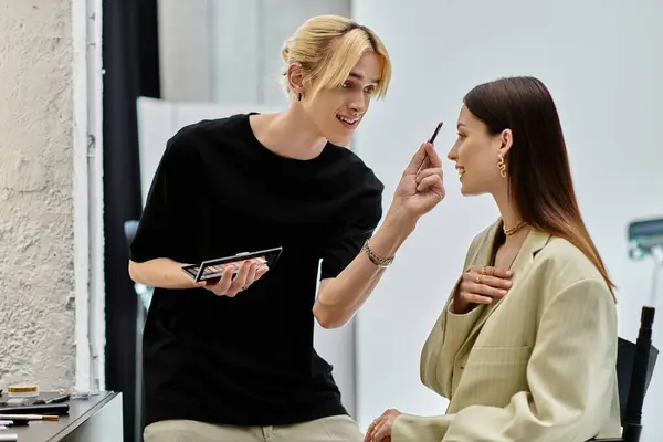 Un maquillador aplica maquillaje a la cara de un cliente. — Stock Photo