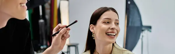 Young stylist applying makeup to young woman. — Stock Photo