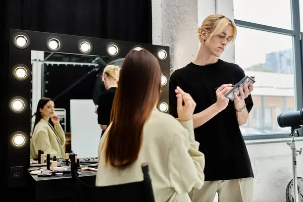 Femme aux cheveux longs se faire maquiller par un artiste professionnel devant un miroir. — Photo de stock
