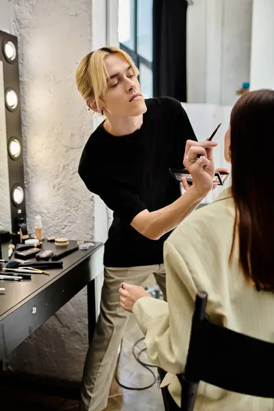 Truccatore di talento creando un look mozzafiato per un cliente femminile in un salone moderno. — Foto stock