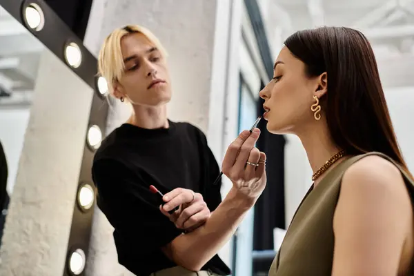 Handsome lgbtq makeup artist enhances womans natural beauty. — Stock Photo