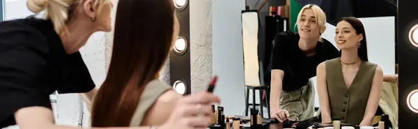 Woman looking in mirror, with her makeup artist. — Stock Photo