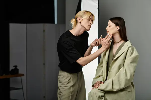 Uomo in camicia nera stunningly applica il trucco al viso delle donne. — Foto stock