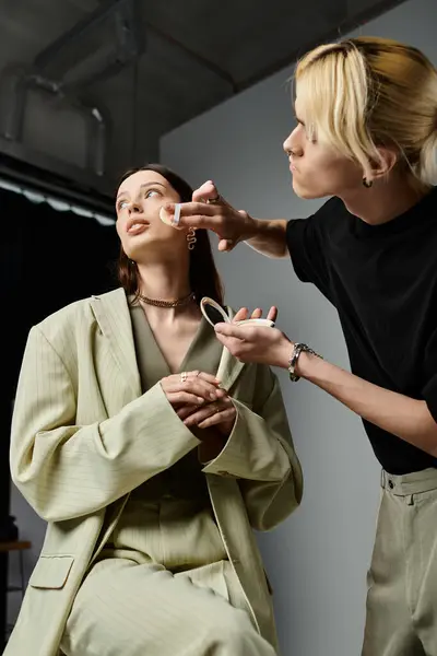 Un maquillador aplica maquillaje a una cara de mujer. - foto de stock