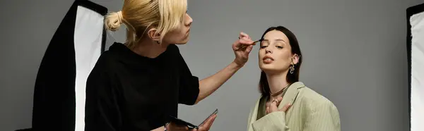 A makeup artist enhances a beauty of a woman with skillful application — Stock Photo