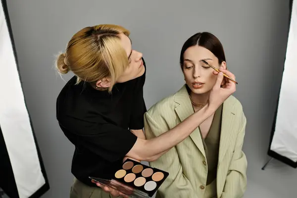 Un maquilleur applique du maquillage sur un visage de femme. — Photo de stock