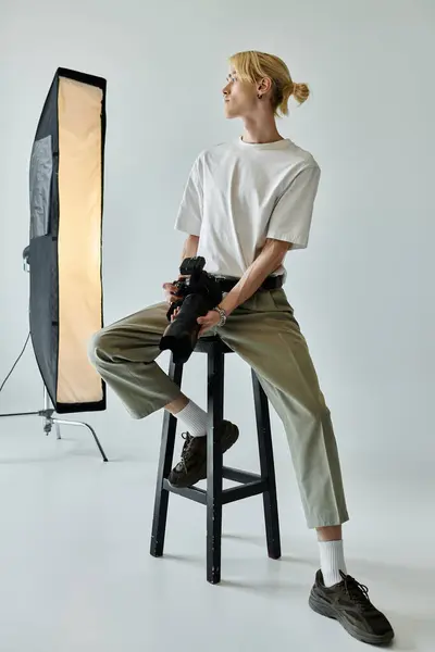 Man sits on stool in front of light. — Stock Photo