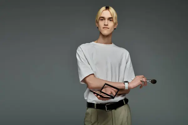 A stylish man in a white t-shirt delicately holds a brush. — Stock Photo