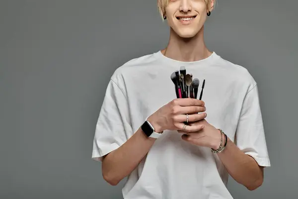 Man elegantly holds various brushes in a colorful display. — Stock Photo