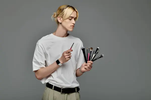 Man gracefully holds a bunch of brushes in her hands. — Stock Photo