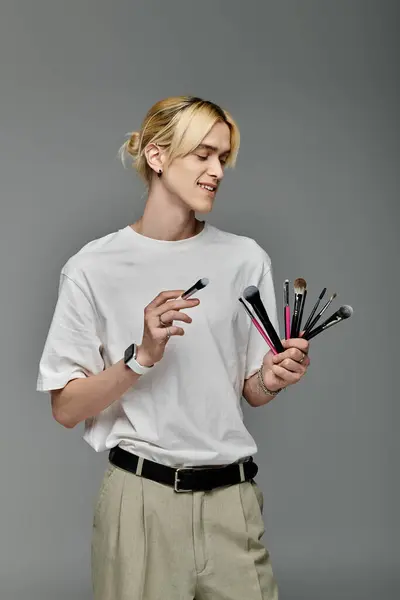 A man holding a variety of colorful brushes. — Stock Photo