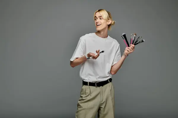 Handsome man holds multiple brushes for makeup. — Stock Photo