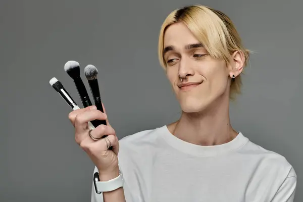 Man gracefully holds a bunch of makeup brushes. — Stock Photo