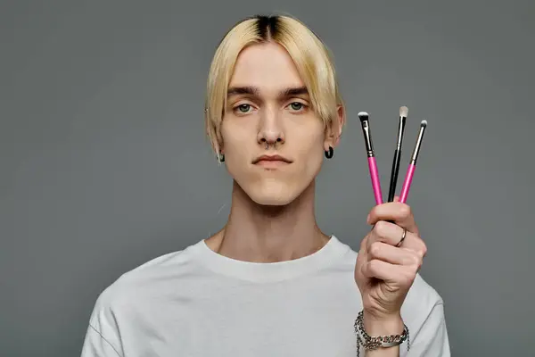 Stylischer Mann präsentiert stolz Make-up-Pinsel. — Stockfoto