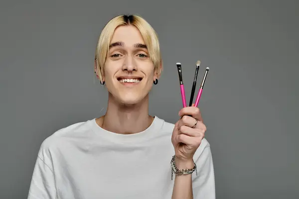 Man confidently holds three brushes in his hand. — Stock Photo