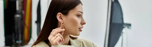 A woman confidently showcasing a pair of gold earrings. — Stock Photo