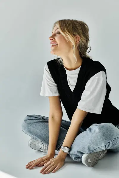 A stylish young woman with blonde hair sits on the ground, her hands comfortably — Stock Photo