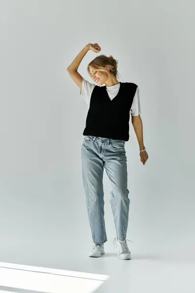 A stylish young woman with blonde hair stands gracefully against a blank backdrop. — Stock Photo