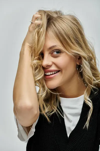 Young woman with blonde hair exudes elegance in a black sweater against a grey background. — Stock Photo