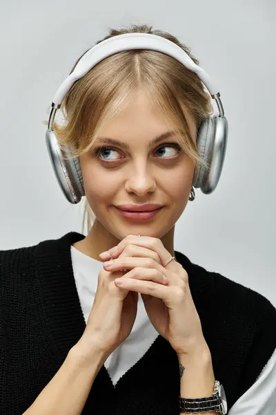 Uma jovem com cabelo loiro usa fones de ouvido, imersa na música tocando, exalando um senso de elegância elegante.. — Fotografia de Stock