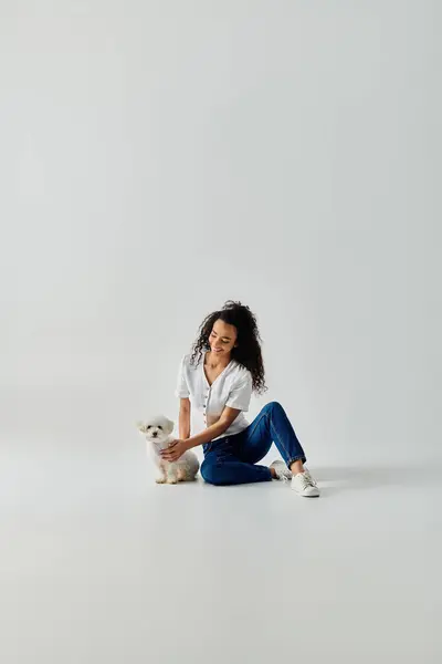 A woman and her cute bichon frise dog bonding while sitting on the floor. — Stock Photo